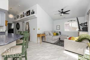 Living room with vaulted ceiling, a ceiling fan, and a chandelier