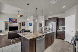 Kitchen featuring appliances with stainless steel finishes, ceiling fan, open floor plan, dark brown cabinetry, and recessed lighting