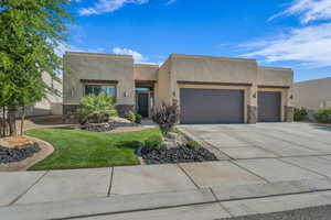 Adobe home with a garage, stone siding, and stucco siding
