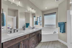 Bathroom with double vanity, connected bathroom, and a garden tub