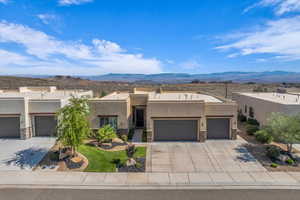 Pueblo revival-style home featuring a mountain view, stucco siding, driveway, and a garage