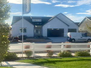 View of front of property featuring a fenced front yard, concrete driveway, and a garage