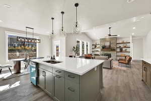 Kitchen with lofted ceiling, light wood finished floors, a fireplace, decorative light fixtures, and recessed lighting