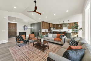 Living area with vaulted ceiling, light wood finished floors, a ceiling fan, recessed lighting, and a chandelier