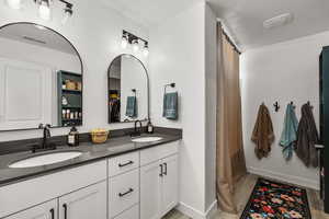 Bathroom featuring double vanity, wood finished floors, a textured ceiling, and a shower with curtain