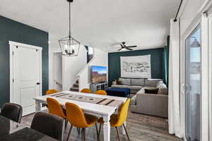 Dining area featuring wood finished floors, healthy amount of natural light, stairs, and a chandelier