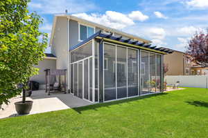 Rear view of house featuring a sunroom, a patio area, and stucco siding