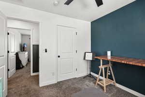 Carpeted home office with ceiling fan and baseboards