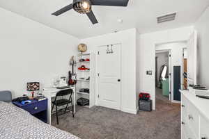 Carpeted bedroom with a desk and ceiling fan