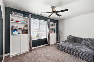 Living area featuring carpet flooring and ceiling fan