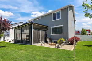 Rear view of house with a sunroom, a fire pit, stucco siding, and a patio area