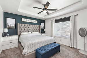 Bedroom with carpet, a tray ceiling, and ceiling fan