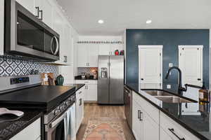 Kitchen featuring stainless steel appliances, white cabinets, a textured ceiling, tasteful backsplash, and recessed lighting