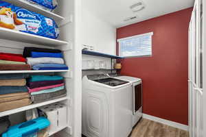 Laundry area with washing machine and clothes dryer and wood finished floors