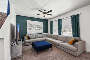 Carpeted living room featuring a ceiling fan and a textured ceiling