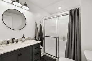 Full bathroom with a shower stall, vanity, and recessed lighting