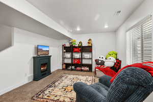 Carpeted living room featuring a lit fireplace and recessed lighting