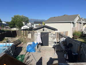 Rear view of property featuring a fenced backyard, a mountain view, and a storage unit