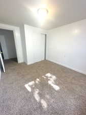 Unfurnished bedroom with a textured ceiling, a closet, and carpet flooring