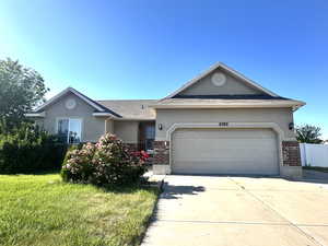 Ranch-style home featuring stucco siding, brick siding, concrete driveway, and an attached garage