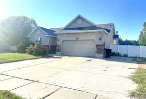 Ranch-style house with an attached garage, driveway, brick siding, and stucco siding