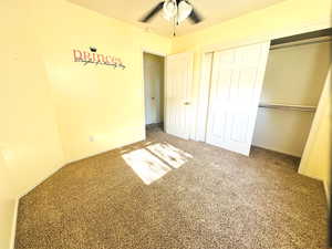 Unfurnished bedroom with carpet floors, a closet, and a ceiling fan