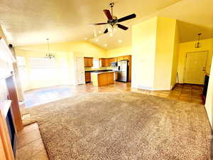 Unfurnished living room with light tile patterned floors, lofted ceiling, a fireplace, ceiling fan, and light carpet