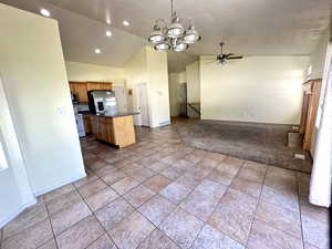 Kitchen featuring appliances with stainless steel finishes, vaulted ceiling, open floor plan, dark countertops, and a chandelier