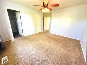 Unfurnished room featuring a ceiling fan and carpet