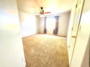 Carpeted empty room with ceiling fan