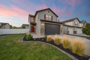 Traditional home with a garage, driveway, stucco siding, and stone siding