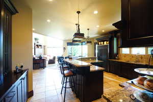 Kitchen with paneled built in fridge, decorative backsplash, recessed lighting, a breakfast bar area, and open floor plan