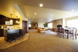 Dining room featuring light colored carpet, recessed lighting, light tile patterned floors, and a stone fireplace