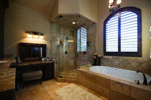 Bathroom featuring a bath, a shower stall, vanity, plenty of natural light, and lofted ceiling