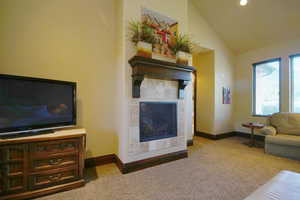 Living area featuring carpet, a fireplace, and lofted ceiling