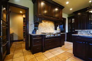 Kitchen featuring stainless steel gas cooktop, decorative backsplash, stone tile floors, recessed lighting, and light stone countertops
