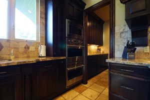 Kitchen featuring appliances with stainless steel finishes, backsplash, and light stone countertops