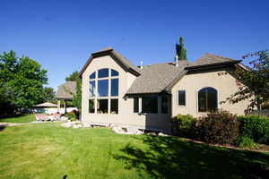Back of house featuring roof with shingles, a yard, and stucco siding