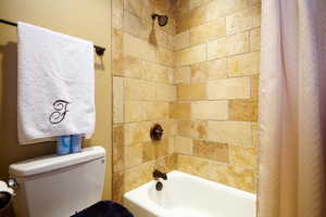 Bathroom with toilet and shower / bath combination with curtain