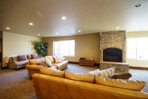 Living area featuring carpet flooring, recessed lighting, and a stone fireplace