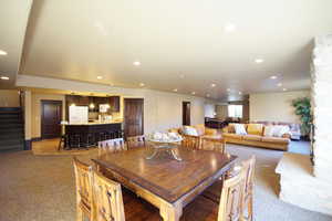 Dining area featuring recessed lighting, stairway, light carpet, and bar