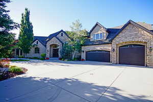 French provincial home featuring stone siding, driveway, and a garage