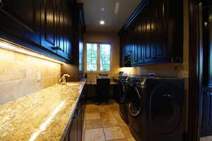 Laundry area with cabinet space, washing machine and clothes dryer, recessed lighting, and light stone finish floors