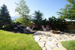 View of grassy yard with a patio area, a fire pit, and a mountain view