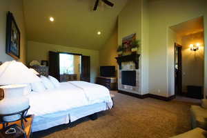 Carpeted bedroom featuring recessed lighting, a fireplace, and high vaulted ceiling