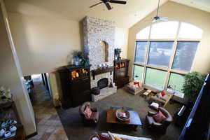 Living room with ceiling fan, healthy amount of natural light, high vaulted ceiling, and a stone fireplace