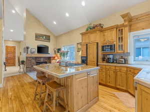 Kitchen with paneled built in refrigerator, black microwave, light wood-type flooring, a center island, and high vaulted ceiling