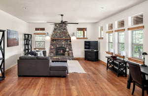 Living room with ceiling fan, light wood-style flooring, a stone fireplace, and recessed lighting