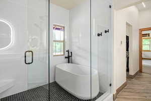 Bathroom featuring wood finished floors, a shower stall, and a freestanding bath