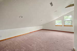 Additional living space featuring carpet flooring, a textured ceiling, vaulted ceiling, and recessed lighting